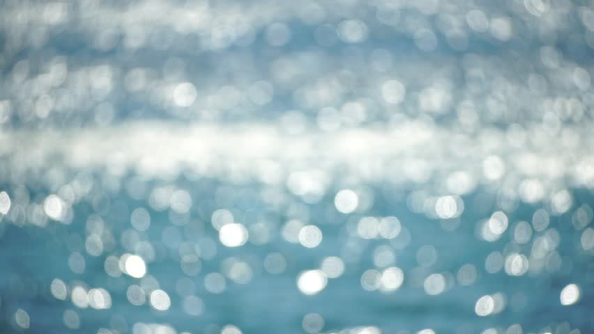 Abstract sea summer ocean sunset nature background. Small waves on golden water surface in motion blur with golden bokeh lights from sun. Holiday, vacation and recreation. Weather and climate change.