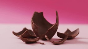 Animation of confetti falling over chocolate on pink background. Sweets, food and celebration concept digitally generated video.