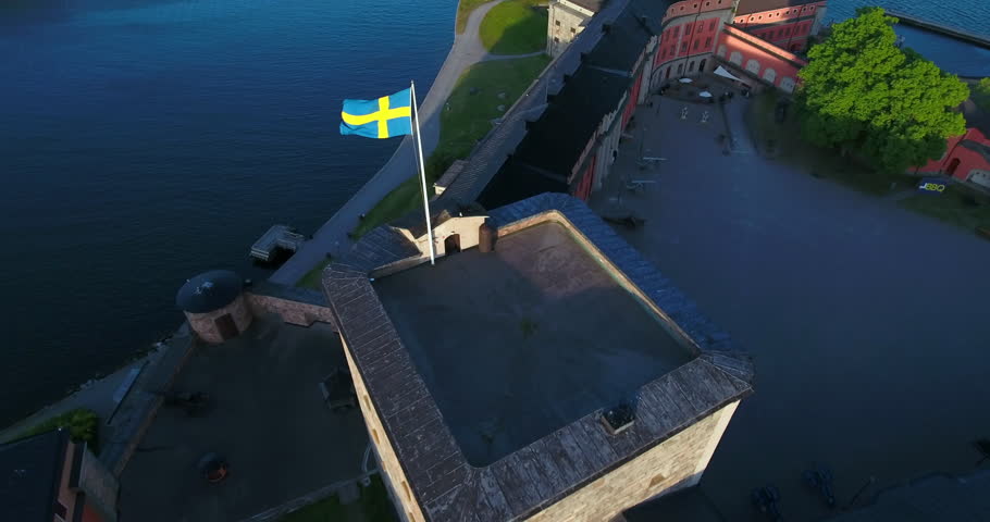 Aerial: The Sun Sets Behind Vaxholm Fortress, Casting A Warm Glow Over The Stone Walls And Surrounding Waters Of The Stockholm Archipelago