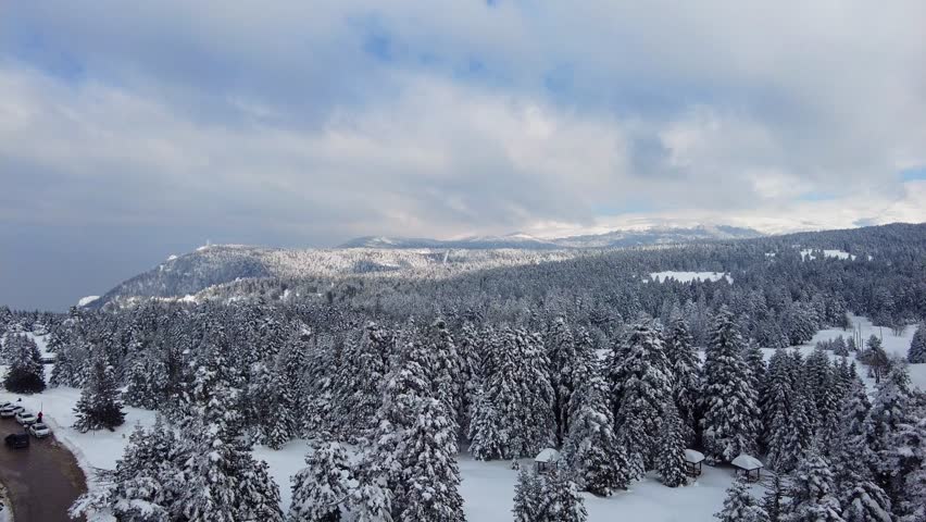 Uludağ mountain aerial view  in a snowy day. the trees are covered with white snow with blue cloudy sky. pan view from above the mount uludag, road with cars on the hills of Bursa city, Turkey Türkiye Royalty-Free Stock Footage #3464506807