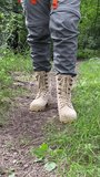 The woman is engaged in hiking in a pine forest. close-up of legs. Vertical video. 