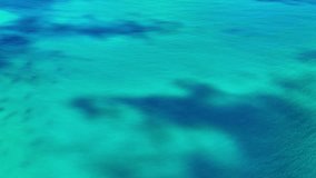 Scenic aerial video footage of the bright turquoise background of the Caribbean Sea. Water surface waves. Drone flying over the ocean. We fly above the sea. Sea sunrise, ripples of ocean waves.