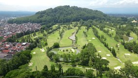 Aerial view of golf course in the middle of Magelang City with small hill on the background. Borobudur International Golf Course with Tidar Mountain.