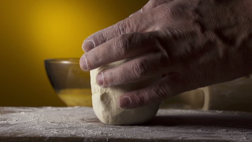 hands kneading bread dough on a cutting board