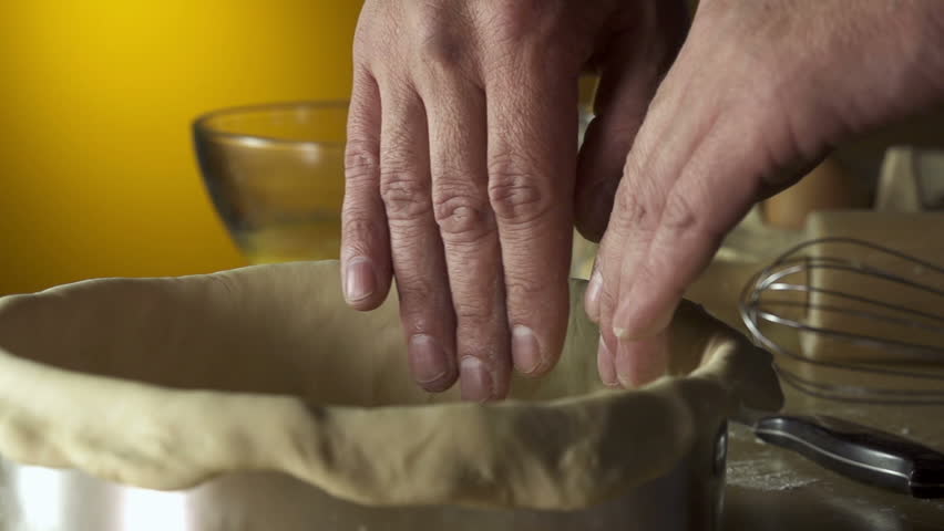 Hands pressing dough down into pie pan.