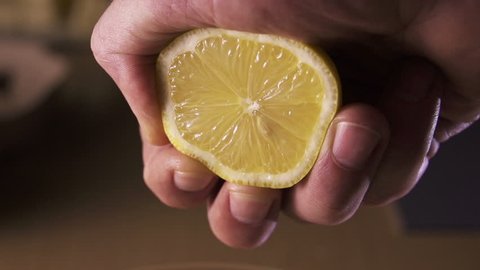 hand squeezing lemon on dark background - Βίντεο στοκ