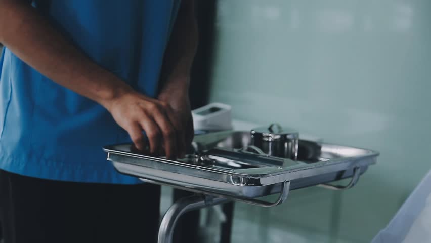 Surgical instruments in the operating room, the surgeon's assistant arranges them on a sterile takani. The concept of medecine, surgery, sterile area. Plastic surgery. Selective focus.