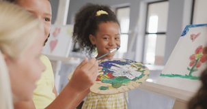 Video of happy diverse girls painting during art lessons at school. primary school education, knowledge and learning concept.