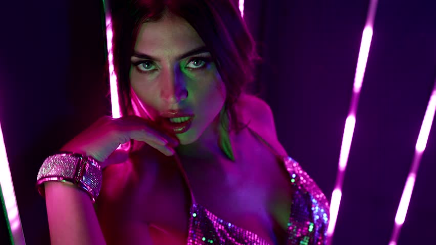 A slender beauty in neon lights dancing at a disco, enveloped in light and energy, which emphasizes her seductiveness and style.