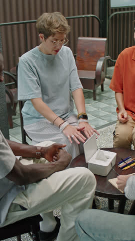 Vertical shot of young upset woman telling about depression and sharing her feelings with group therapy patients and psychologist