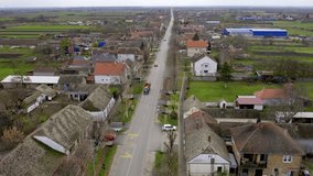 Drone captures a tractor towing a cart with passengers driving through village