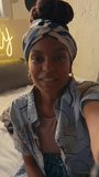 Vertical POV UGC of smiling young African American lady in bandana and stylish clothes speaking happily looking at camera and recording video for blog in grunge house with inscription Good Vibes Only