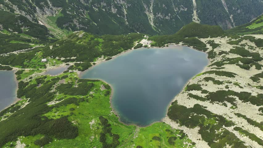 Dramatic aerial view of blue mountain lake in the Beautiful mountain region. High Tatras in Poland or Slovakia. Morskie oko. Dramatic snow covered mountain peaks backdrop. Five valley lake