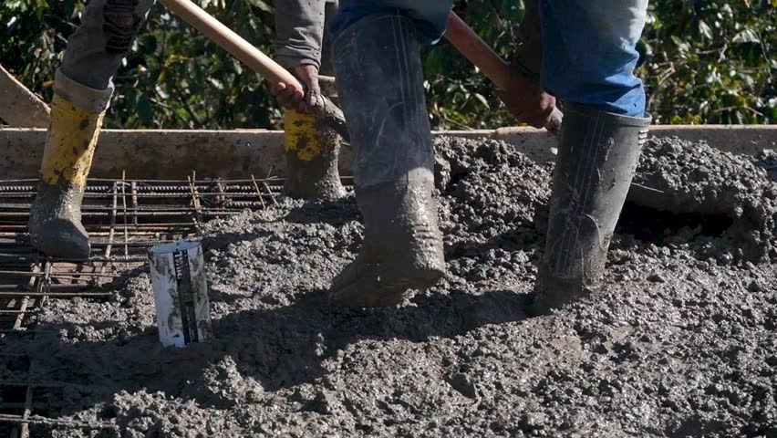 Closeup shot of a constructors working with concrete and cement during daytime. 