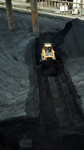 Crawler bulldozer works on coal mines. Extractive industry, anthracite. Aerial view.