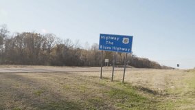 Highway 61, the Blues Highway sign along side of the road in Mississippi with vehicles driving by and wide shot video stable.