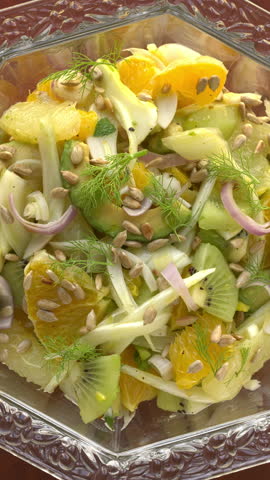 Top view of citrus salad with fennel and avocado in a cristal glass bowl. Table spin. Vertical video.