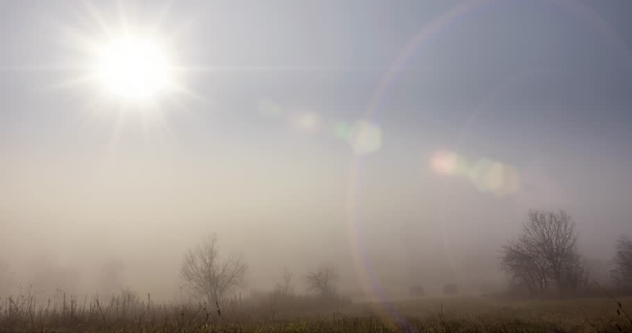 4k mountain meadow timelapse at the autumn sunrise time. Wild nature and rural haystacks on grass field. Morning fog, sun rays and trees. Motorised dolly slider