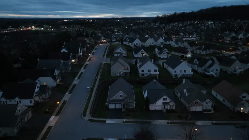Aerial truck shot of dark neighborhood at night. Development with town lights in background.
