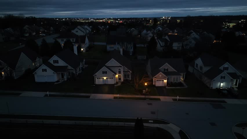 Aerial truck shot of American neighborhood at night. Blue hour dusk sky over houses and homes.