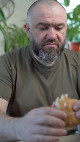 Bearded man eating a big burger with meat in cafe Royalty-Free Stock Footage #3465311635