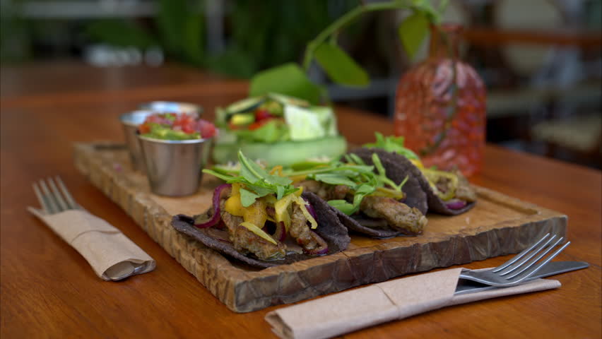 Slow motion close up of mexican beef tacos made in Yucatan using traditional spices called recaudo on blue corn tortillas and red onion