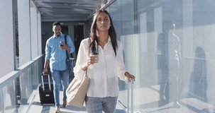 Video of diverse man and woman walking with suitcases and coffee. business professionals and working in office concept.