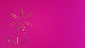 Paperclips flower. Daisy made from office paper clips moves on a pink background. Stop motion animation with stationery and space for text, design, advertising.