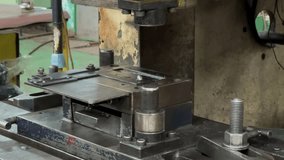 Process of pressing iron plates using iron molds and press machines. Running iron press machine. Close up shot of operator hand put metal plate on the iron mold of press machine.