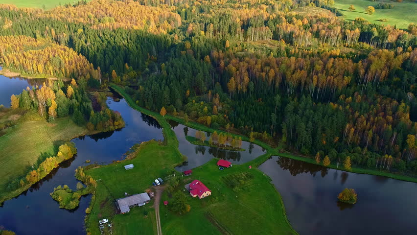 Rural homestead surrounded with lakes and autumn forest, aerial view