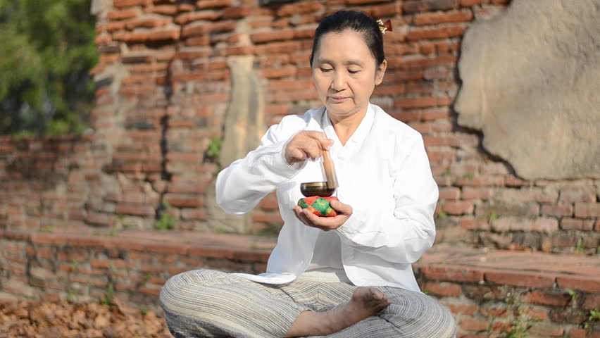 Woman playing a tibetan bowl,  traditionally used to aid meditation in Buddhist cultures. 