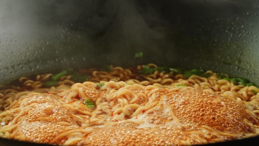 Cooking instant noodles in boiling water with spices close-up. Asian fast food. Instant noodles, or instant ramen, is a type of food consisting of noodles sold in a precooked and dried block with