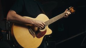 Young musician man sitting and playing acoustic guitar among music equipment in studio close-up. Guitarist plays melody  - Powered by Shutterstock - Get 15% off with code: PIKWIZARD15