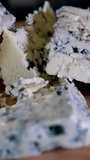 Rotation cheese on black slate plate. Delicious cheese Dorblu on the cutting board on background. High quality 4k footage vertical video