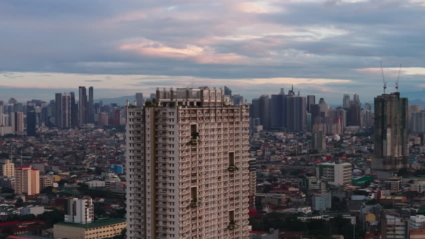 Fly around Torre de Manila building. Modern tall residential high rise tower and twilight skyline in background. Manila, Philippines