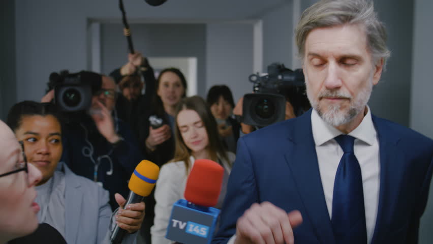 Irritated politician refuses to give interview for the TV press and quickly walks in corridor of government building. Busy diplomat or minister surrounded by crowd of news journalists. Press campaign.