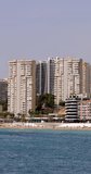 Portrait footage of the town of Benidorm in Spain showing the West Beach Promenade known as The Poniente Beach in the summer time with people relaxing and having fun.