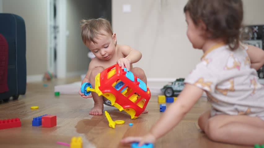baby group child playing toy car bus on the floor in kindergarten. happy family kid concept. baby group playing red bus toy bus indoors. child boy blond plays with lifestyle a toy car in kindergarten