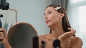 Young woman making beauty and cosmetic tutorial video content for social media. Beauty blogger smiles to camera while showing how to beauty care to audience or followers. Adit