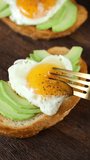 Eating poached egg on avocado toast. Vertical video