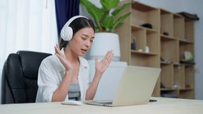 Young asian woman wearing headset while working on computer laptop at house. Work at home, Video conference, Video call, Student learning online class