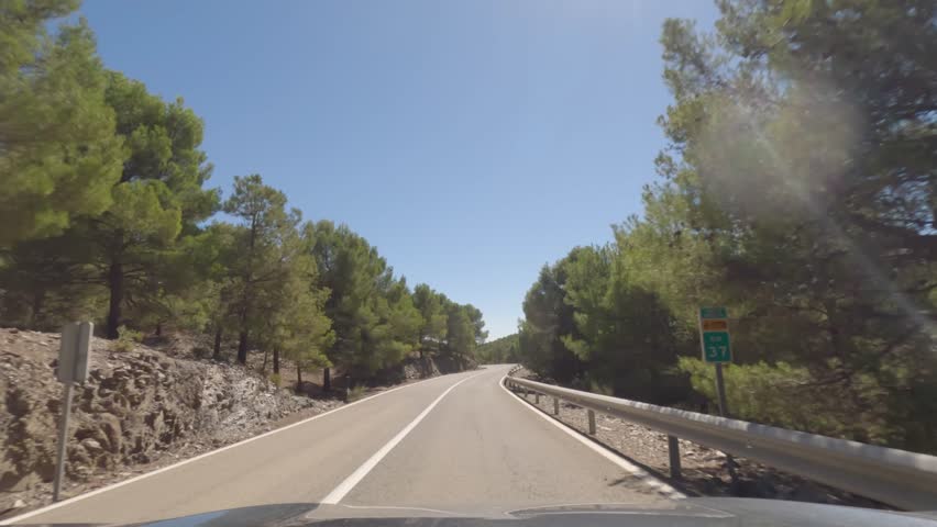 First person view, FPV, from dashcam of car driving mountain road from Calar Alto Observatory to Tabernas Desert in Almeria, Andalusia, Spain, Europe. Road trip in POV, with bright, sunny, clear sky