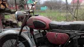 Old motorcycle in the dust. Red retro moto. Defective motorcycle, needs repair. A dirty rural gasoline motorcycle, next to it in the yard around the mess - Powered by Shutterstock - Get 15% off with code: PIKWIZARD15