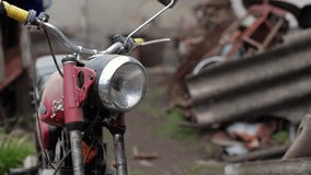 Old motorcycle in the dust. Red retro moto. Defective motorcycle, needs repair. A dirty rural gasoline motorcycle, next to it in the yard around the mess - Powered by Shutterstock - Get 15% off with code: PIKWIZARD15