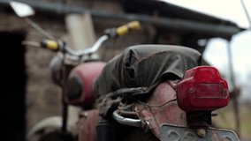 Old motorcycle in the dust. Red retro moto. Defective motorcycle, needs repair. A dirty rural gasoline motorcycle, next to it in the yard around the mess - Powered by Shutterstock - Get 15% off with code: PIKWIZARD15