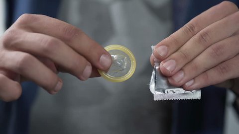 Male hand opening condom package before camera, contraception, close-up