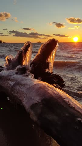 Winter on the seashore. Natural ice sculptures created by wind and wave. Sunset light background. Royalty-Free Stock Footage #3466064389