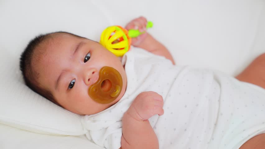 Asian mother gives a pacifier dummy to mouth infant baby girl on a bed. newborn baby sleeping home. Lifestyle newborn with a suck pacifier. Happy family kid dream concept. Pacifiers calm babies. Royalty-Free Stock Footage #3466076007