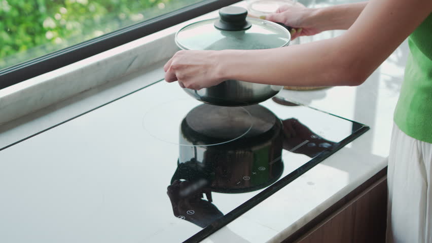 Close-up of hands adjusting temperature on modern induction stove with stainless steel pot, concept of home cooking Royalty-Free Stock Footage #3466112183