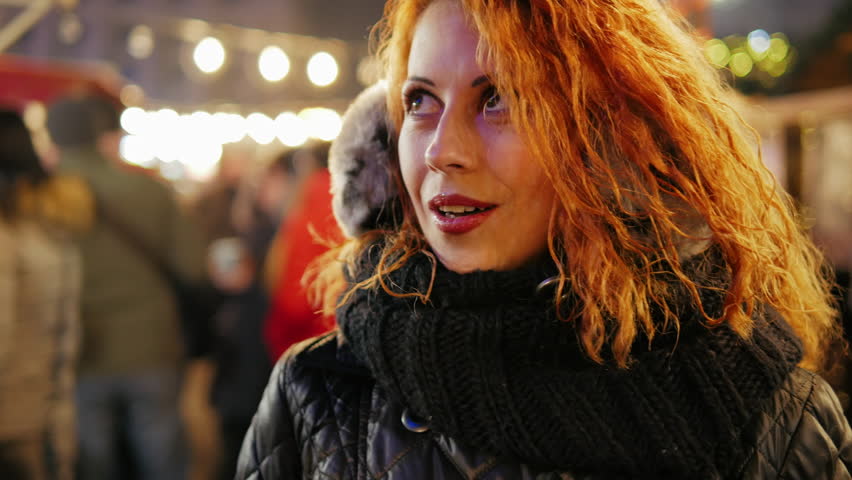 Cute curly red hair young girl walking at winter city holiday fair close-up